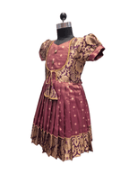 A traditional Indian dress displayed on a black dress form mannequin against a white background. The dress is maroon with gold and beige floral patterns and has short puff sleeves. - House of Kritee
