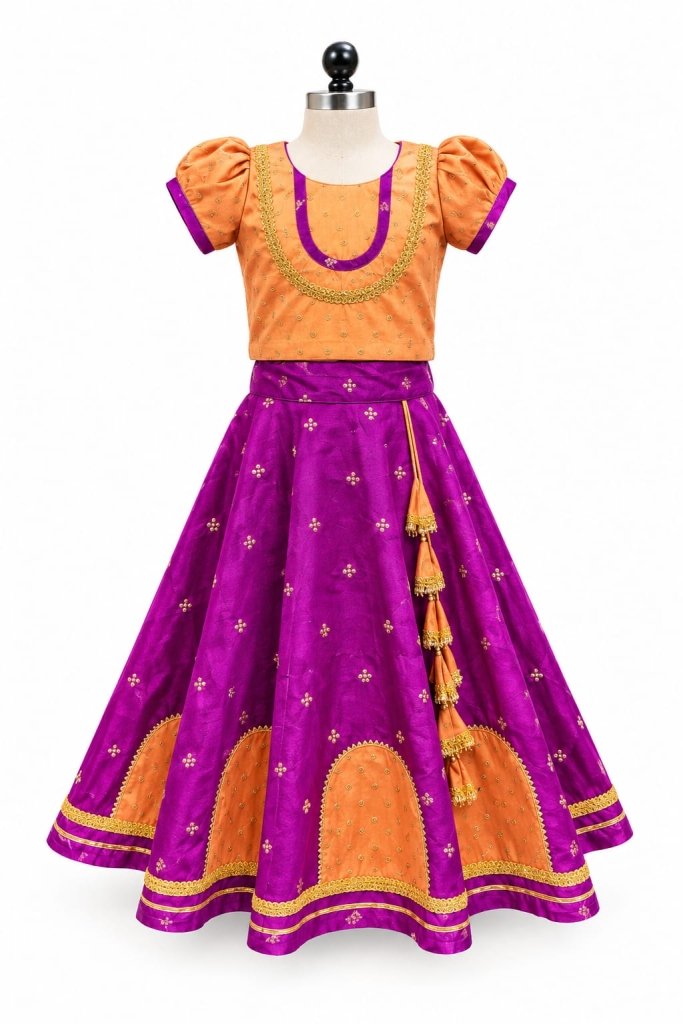 A young girl smiles while wearing a traditional orange and purple silk blend lehenga choli, featuring intricate pearl and gold embroidery and a decorative tassel